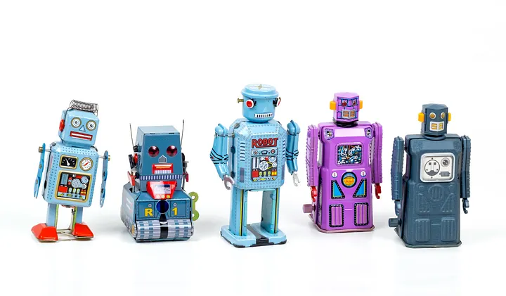 A lineup of five vintage tin toy robots of varying sizes